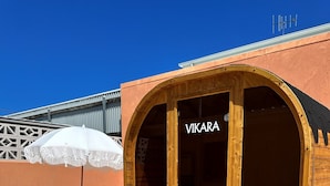 A wooden sauna with a glass door labeled "VIKARA" in a tiled outdoor area. - Pacific Sun Bargara  (Bargara)