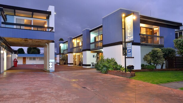 A modern motel with a two-story structure, a covered parking area, and a sign indicating availability for short-term stays. - Waikanae Beach Motel (Gisborne)