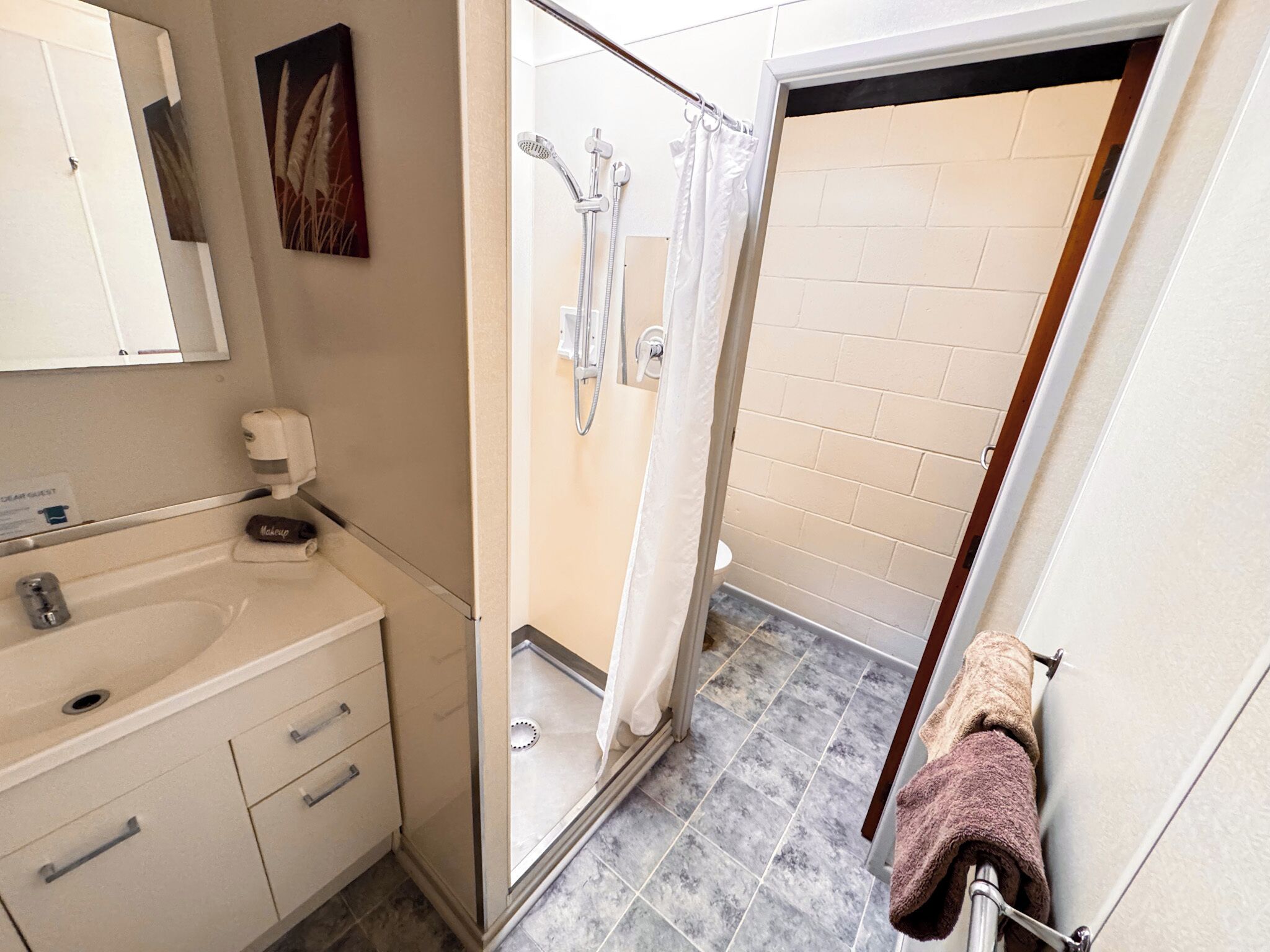 A bathroom with a shower, a sink, and a towel rack.