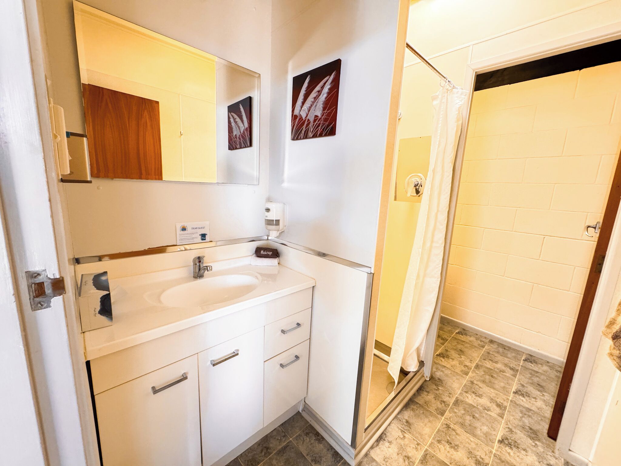 Baño con lavamanos, espejo y zona de ducha.