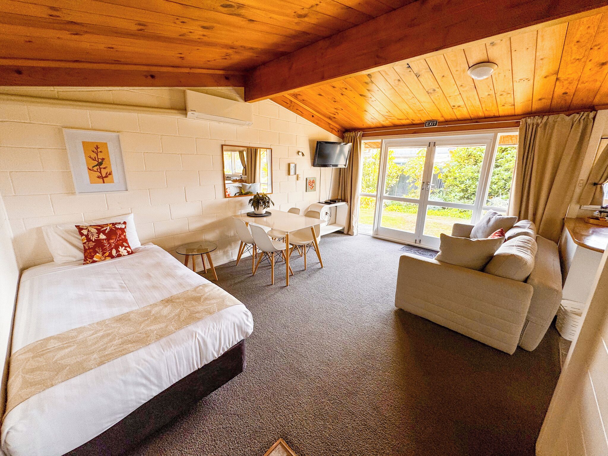 A room with a bed, a sofa, a dining table, and a TV.