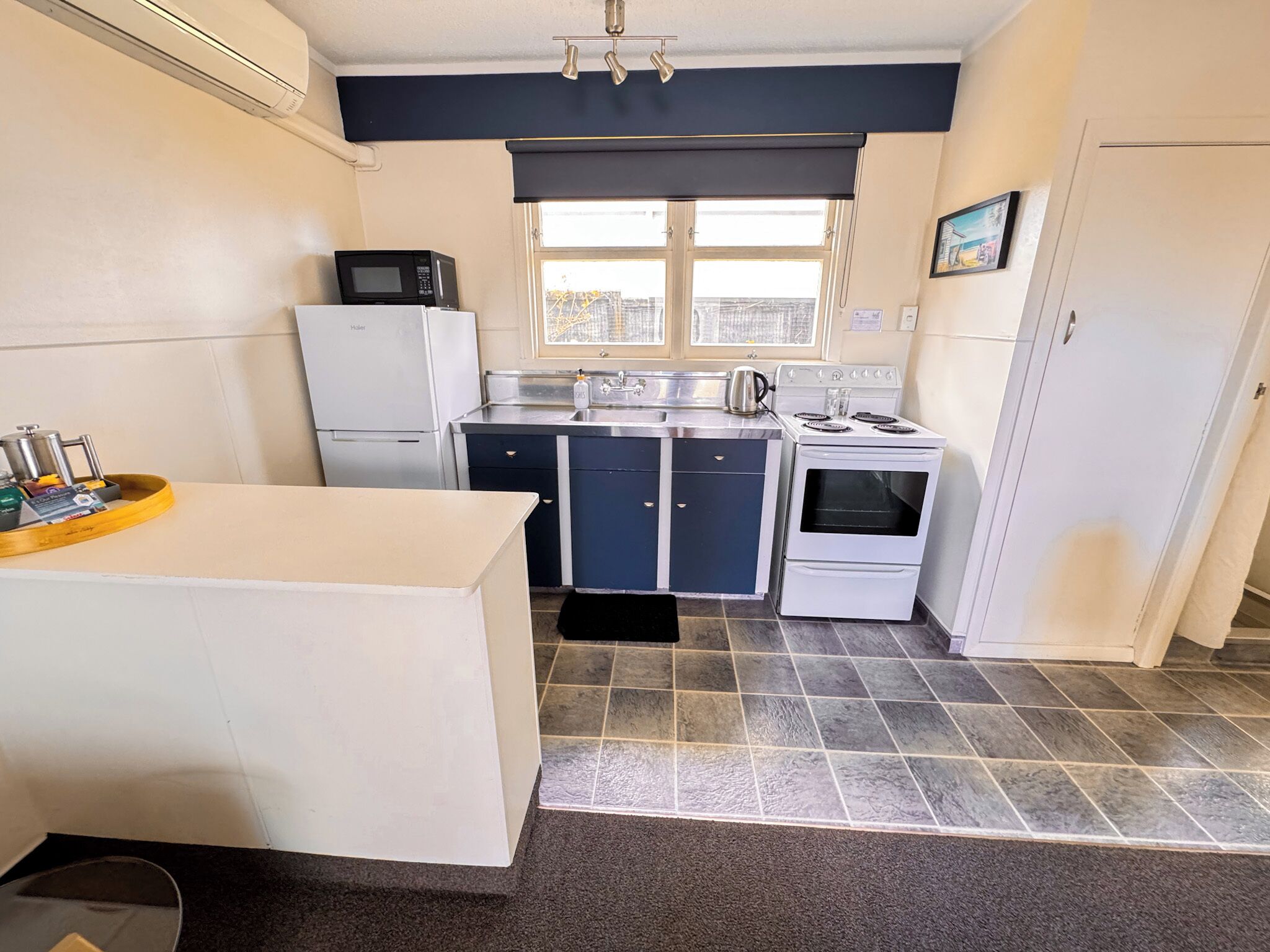 A compact kitchen with a refrigerator, stove, microwave, and a sink.