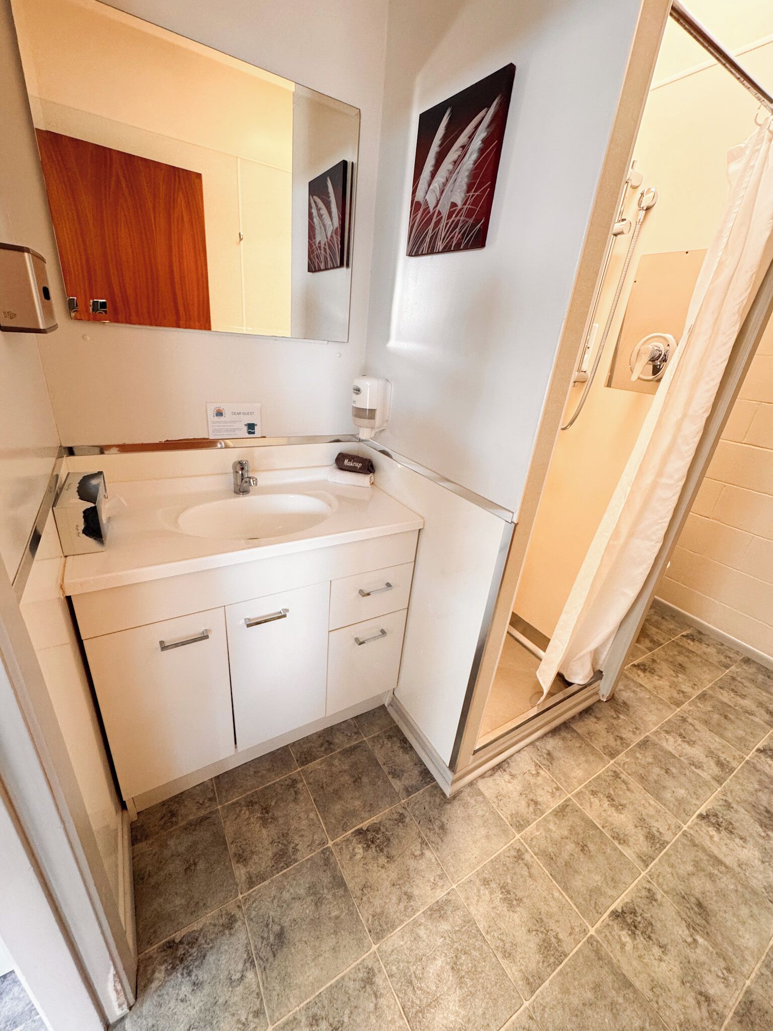 A bathroom with a double sink, a mirror, a towel rack, and a shower area.