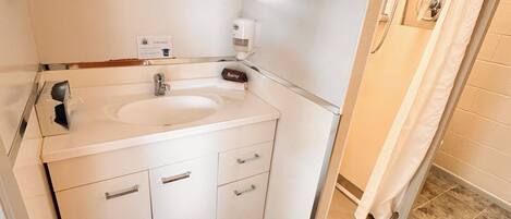 A bathroom with a double sink, a mirror, a towel rack, and a shower area.