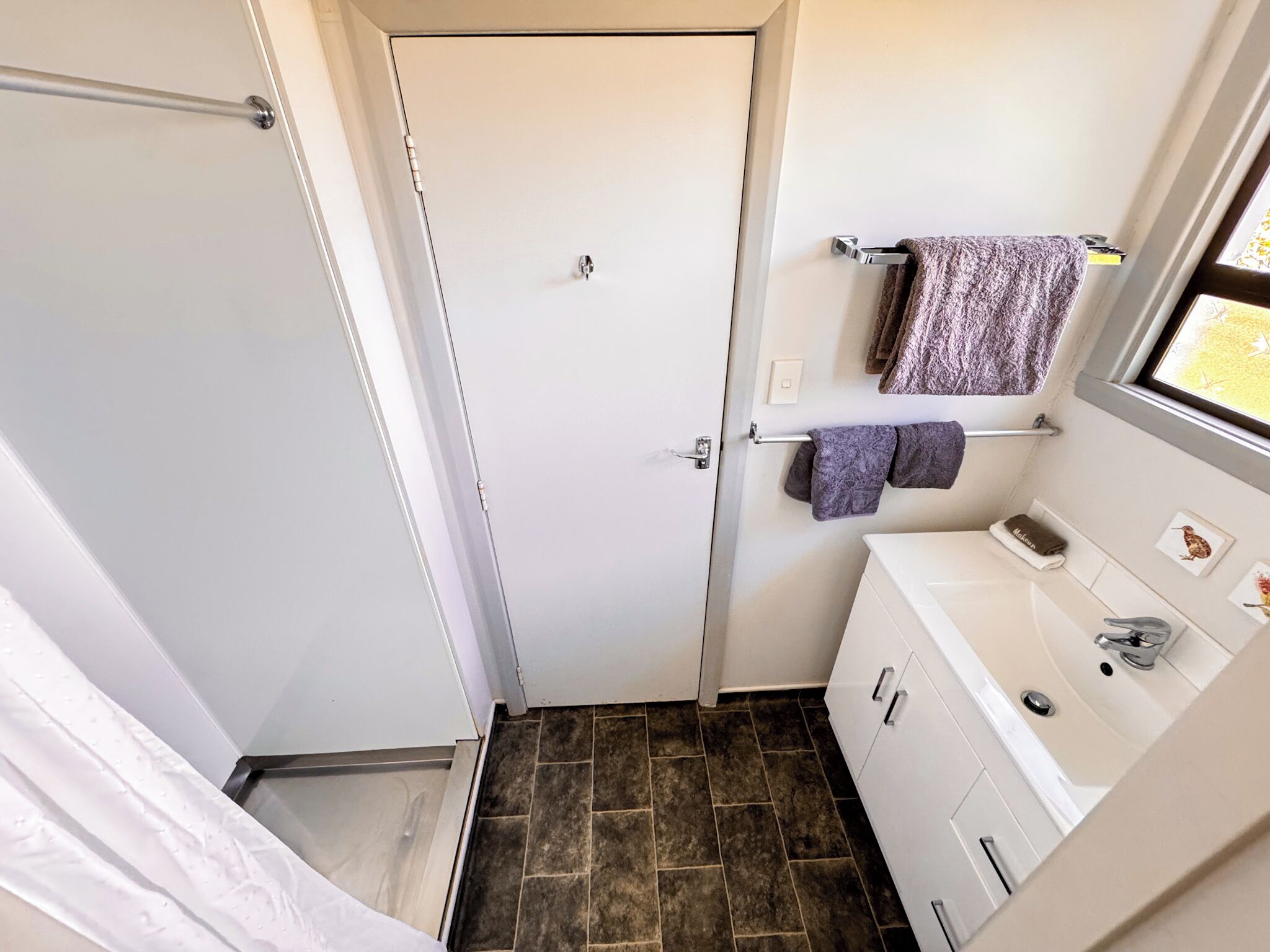 A compact bathroom with a shower, a toilet, a sink, and a towel rack.