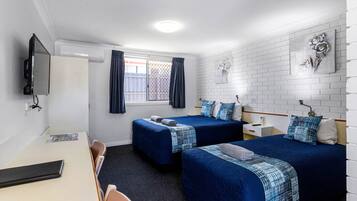 Habitación de hotel con dos camas, un escritorio, un televisor y una ventana con cortinas.