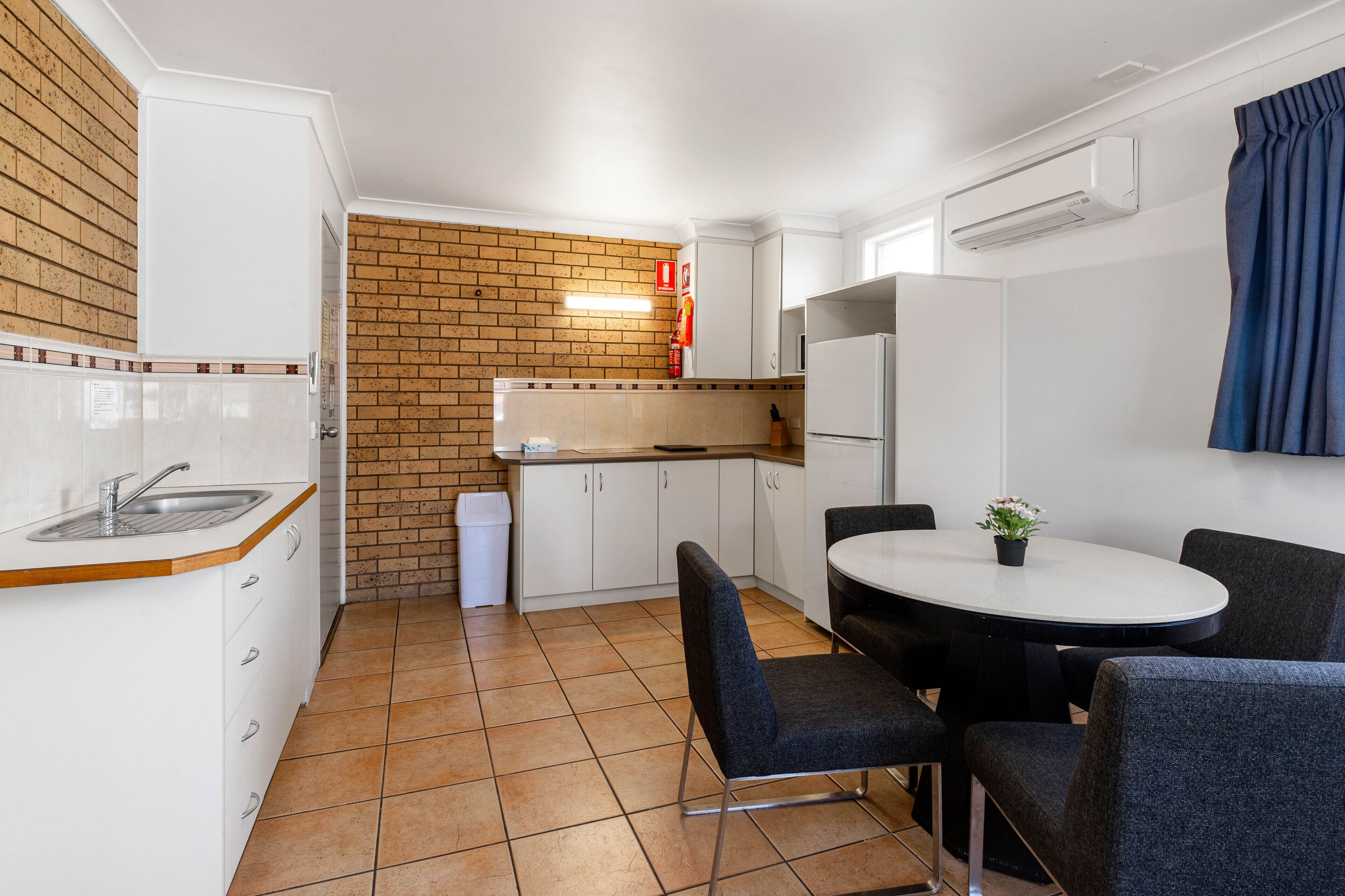 Een compacte keuken met witte kastjes, een spoelbak en een betegelde achterwand.
