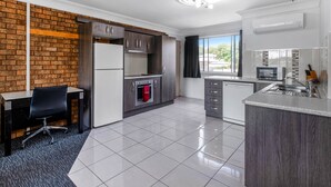 A modern kitchen with a brick accent wall, a built-in oven, and a large window. - Leichhardt Motor Inn (South Toowoomba)
