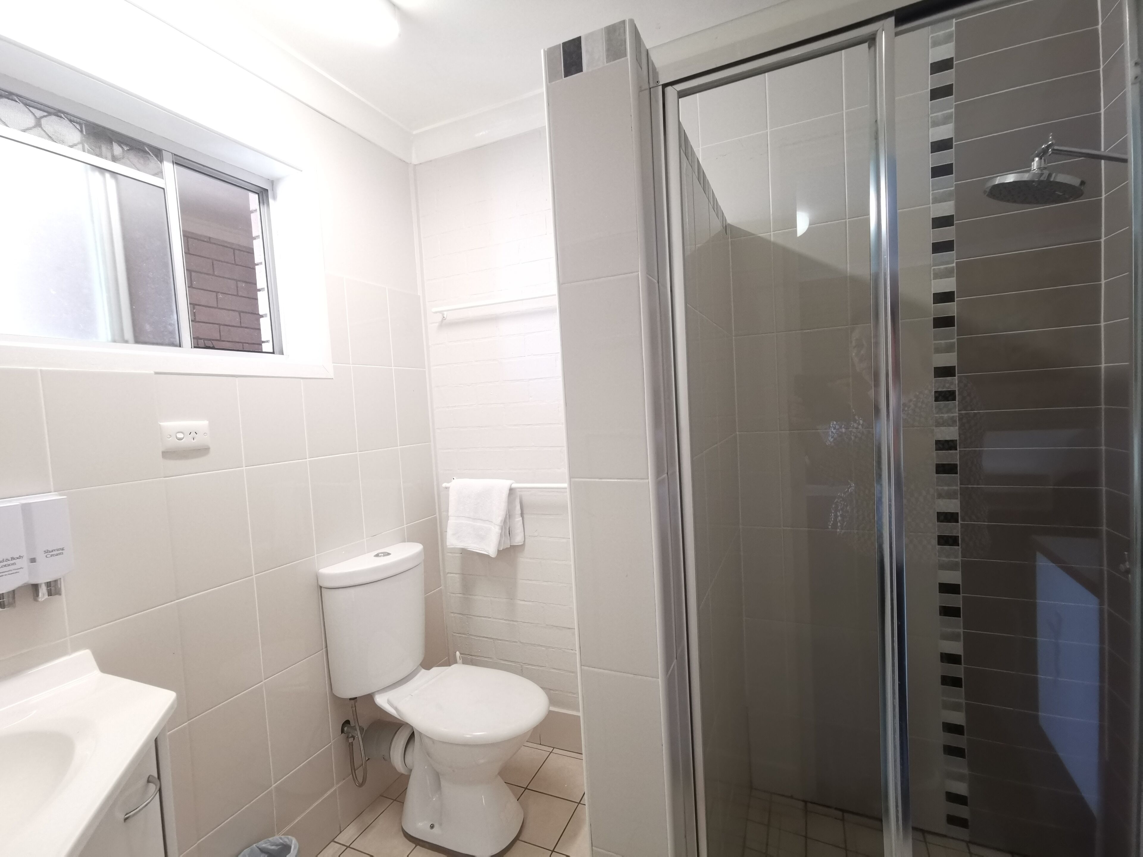 A bathroom with a toilet, sink, and a glass-enclosed shower.