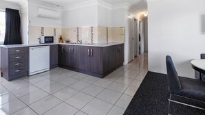 A modern kitchen with a dishwasher, microwave, and dark cabinets. - Leichhardt Motor Inn (South Toowoomba)