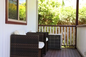 A covered porch with wicker furniture and an air conditioning unit.