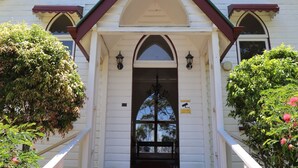 Un edificio blanco con techo marrón, una puerta principal y una escalera que lleva a la entrada.