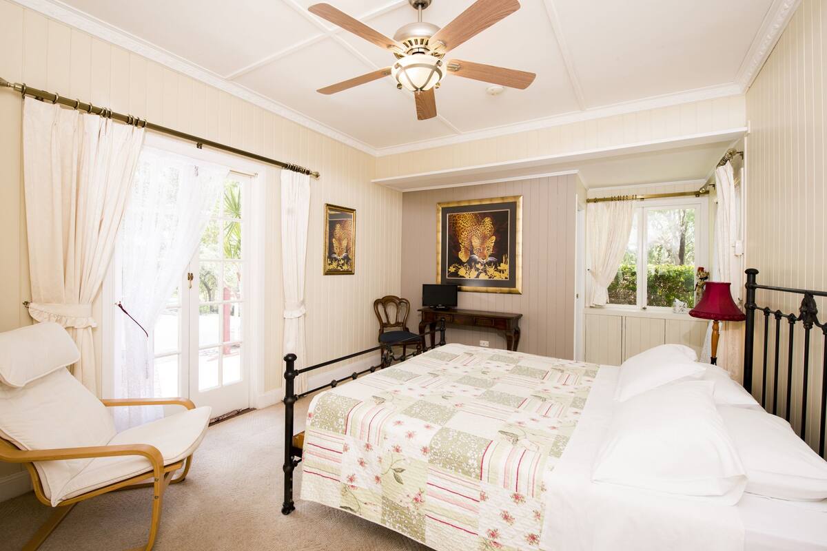 Ein Schlafzimmer mit Bett, Stuhl, Schreibtisch und Deckenventilator.