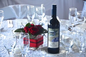 A table set for a formal event with a bottle of wine, glasses, and a red box with roses.