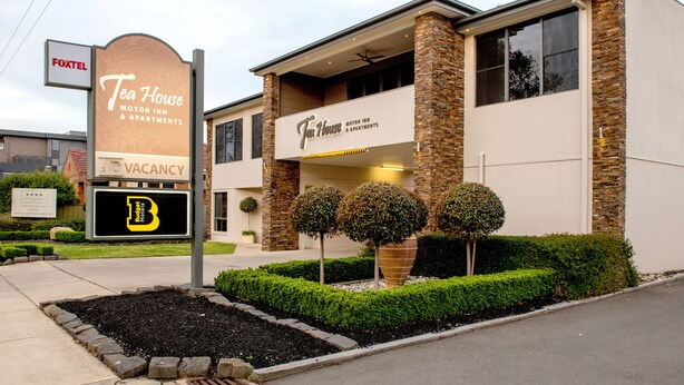 A building with a sign for "Tea House Motor Inn & Apartments" and a "Vacancy" sign.