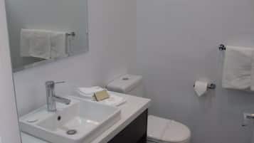 A modern bathroom with a white sink, mirror, and toilet.