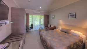 Une chambre d’hôtel avec un grand lit, un bureau, une chaise, une télévision et un balcon avec des rideaux.
