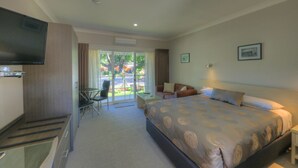 Une chambre d’hôtel avec un lit, une télévision, un bureau et une chaise.