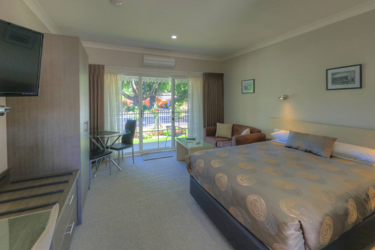 A hotel room with a bed, a TV, a desk, and a chair.