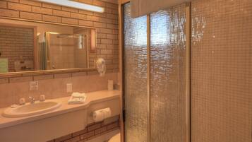 Un baño con lavamanos, espejo y zona de ducha.