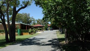 A quiet residential street with houses, a clear sky, and lush greenery. - Acclaim Kingsway Tourist Park (Madeley)