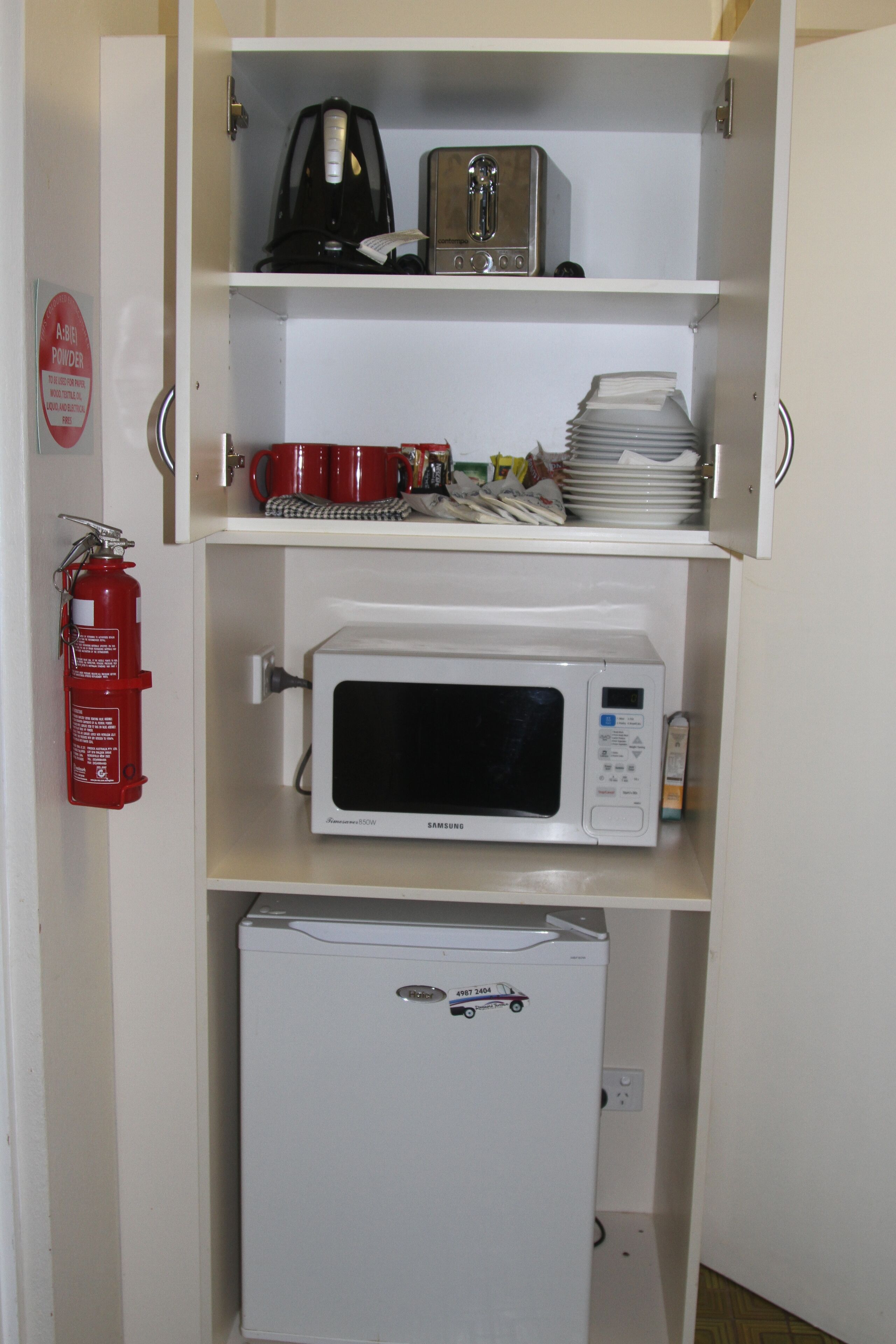 A kitchen with a microwave, a coffee maker, and a refrigerator.