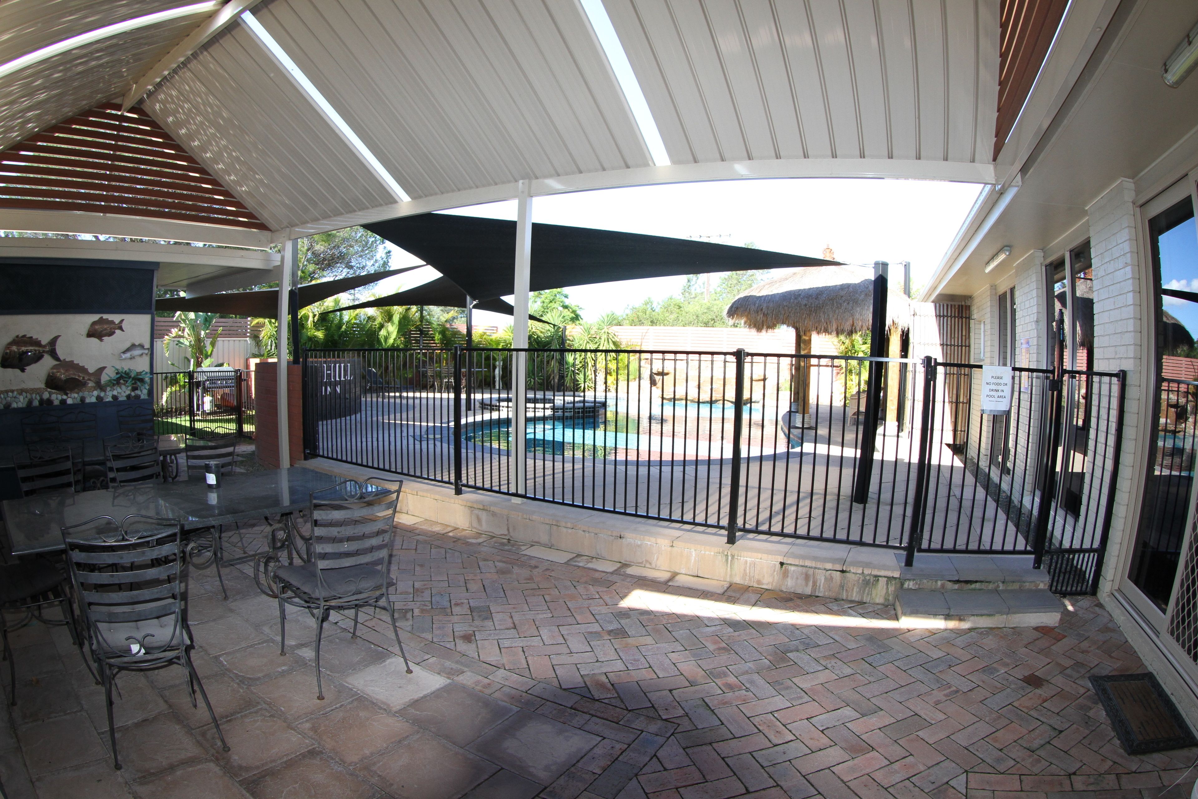 Un patio exterior con piscina, mobiliario cubierto y zona de natación cercada.