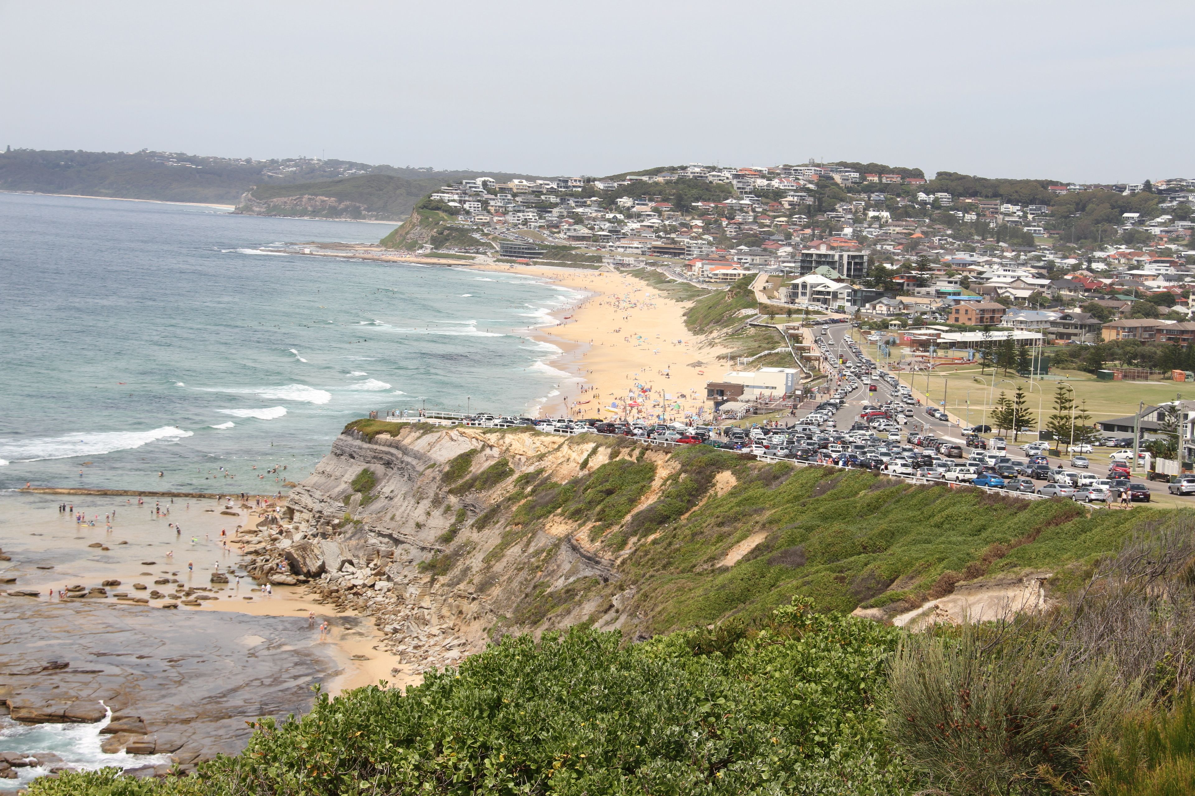 A coastal town with a beach, rocky cliffs, and a densely packed residential area.