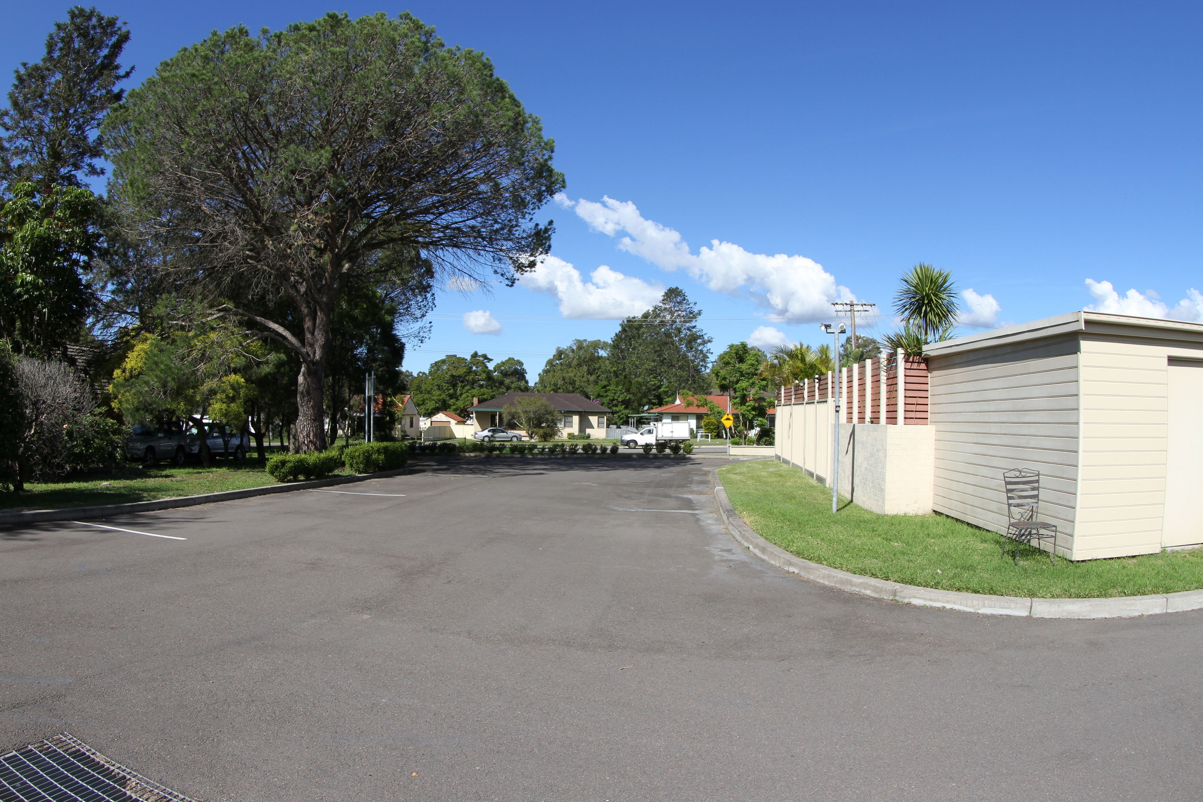 A residential street with houses, a parking lot, and a grassy area.