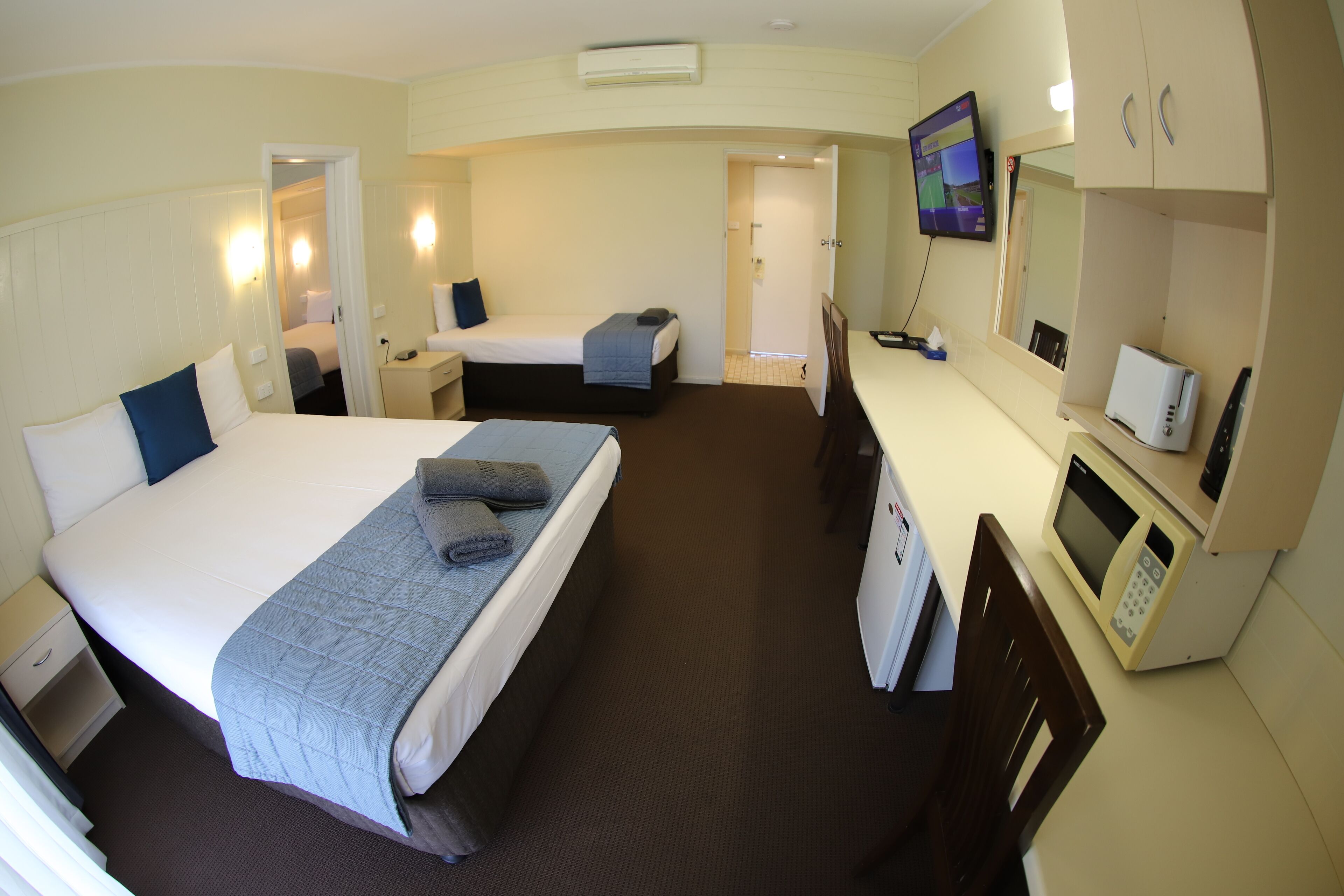 Habitación de hotel con una cama grande, un escritorio con computadora, microondas y televisión.