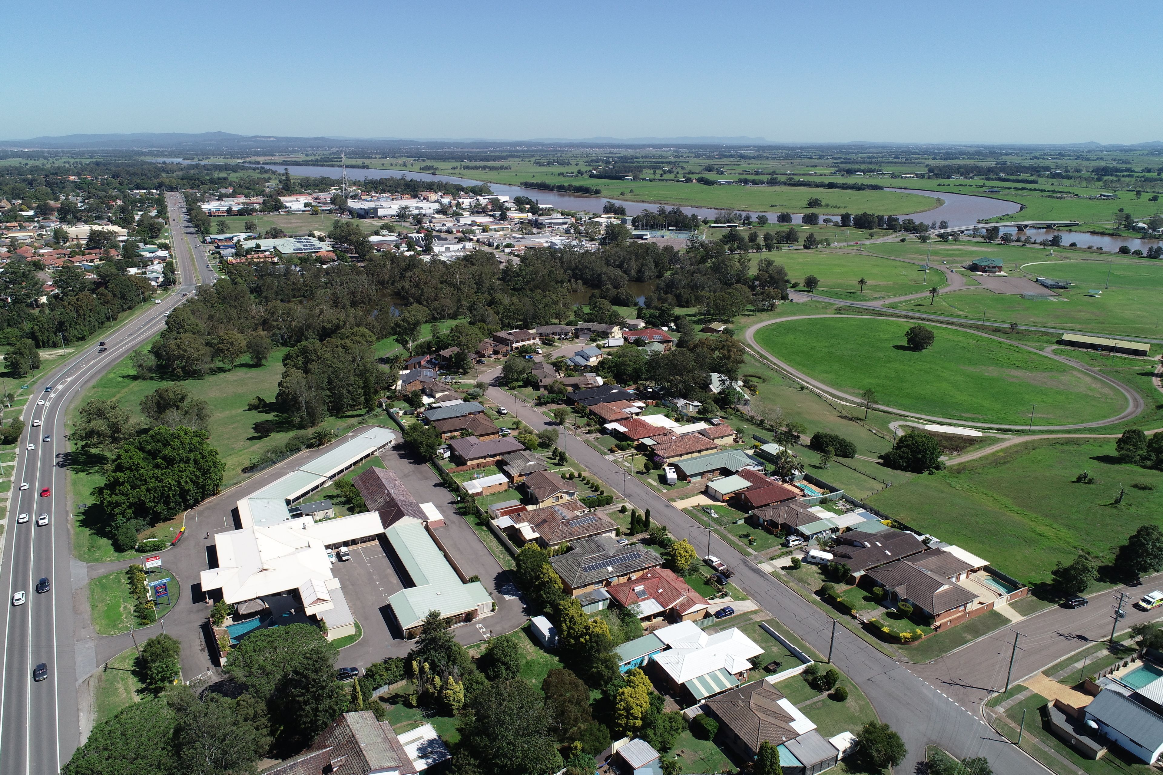 An aerial view of a residential area with houses, roads, and a river.