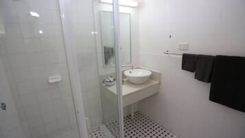 A bathroom with a glass-enclosed shower, a white sink, and a tiled floor.