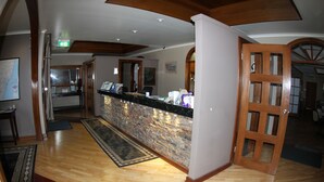 Una zona de recepción con suelo de madera, pared de piedra y mostrador.