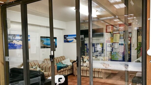 Un espace d’accueil comprenant un canapé, une table basse et une porte vitrée donnant sur un salon avec un canapé à motifs et une petite table.