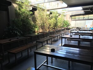 A spacious indoor seating area with long tables and benches, surrounded by lush greenery and a high ceiling with skylights. - Strathfield Hotel (Strathfield)