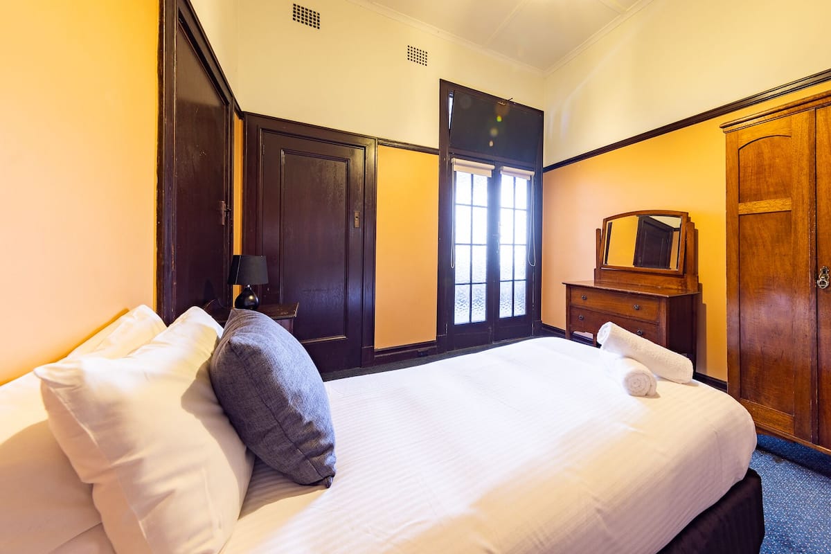 A hotel room with a large bed, a dresser, a mirror, and a wardrobe.