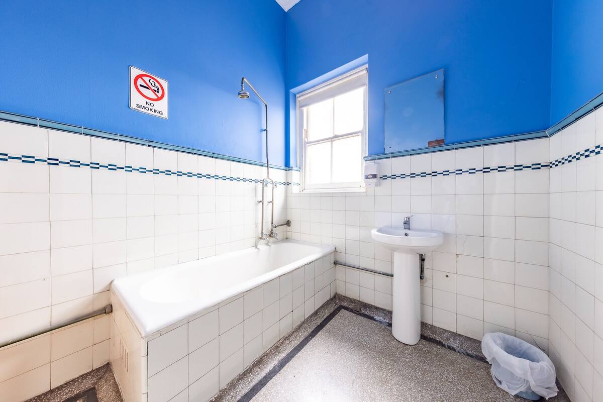 A bathroom with a bathtub, sink, and a no-smoking sign.