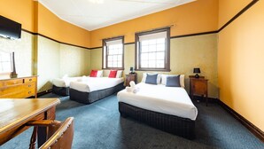 Habitación de hotel con dos camas, un tocador de madera, un escritorio y una silla.