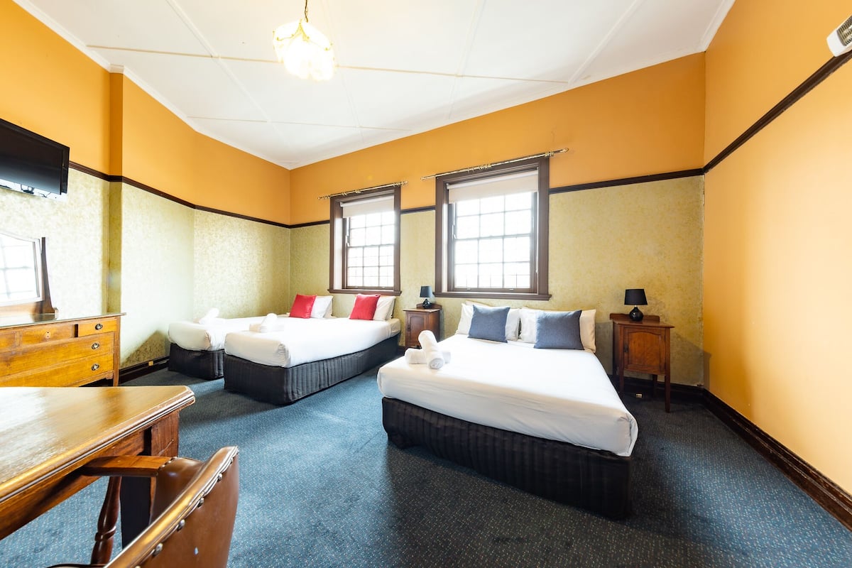 A hotel room with two beds, a wooden dresser, a desk, and a chair.