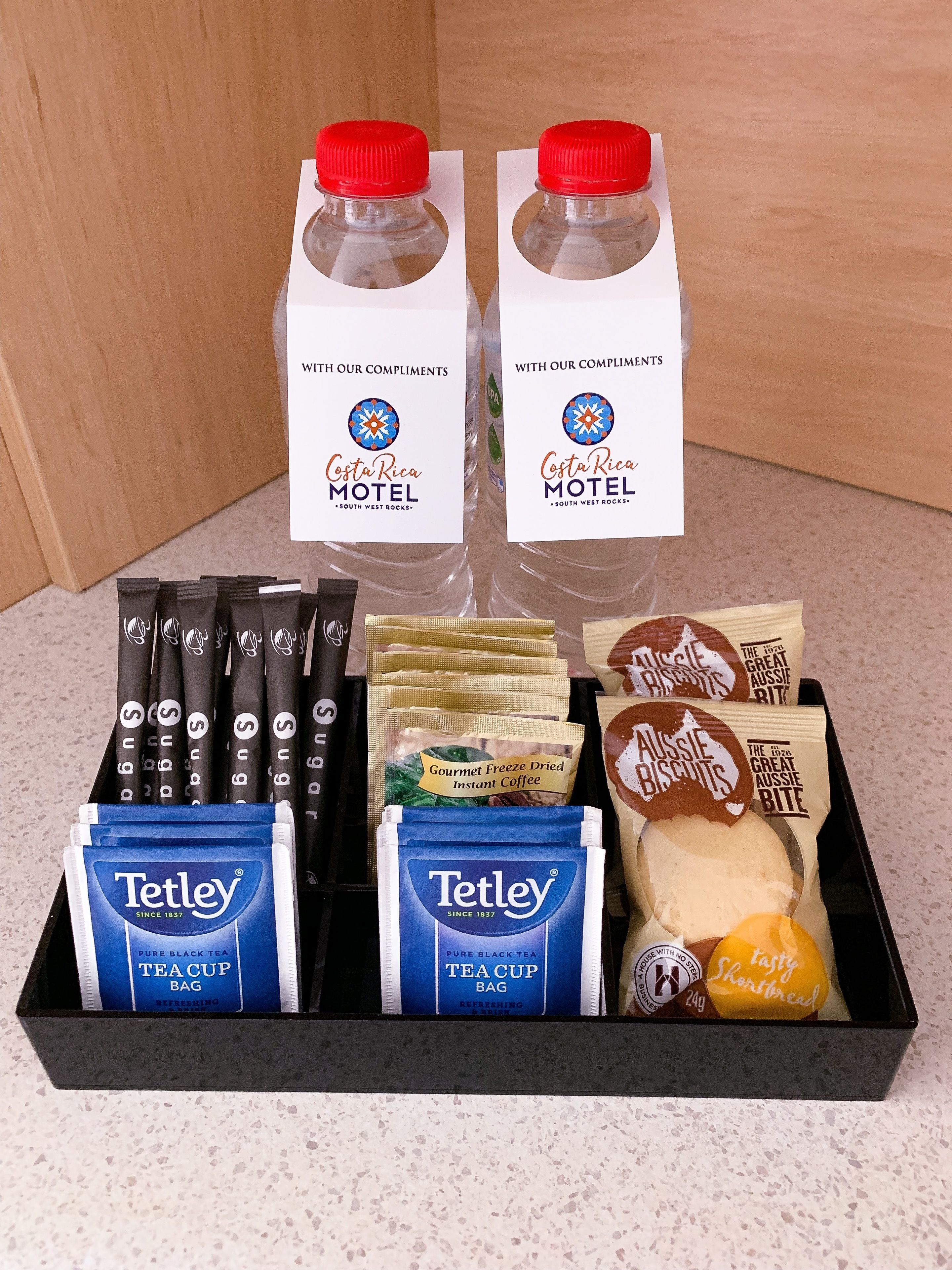 Un panier-cadeau contenant des articles tels que du café instantané, des sachets de thé, des biscuits et une miche de pain.