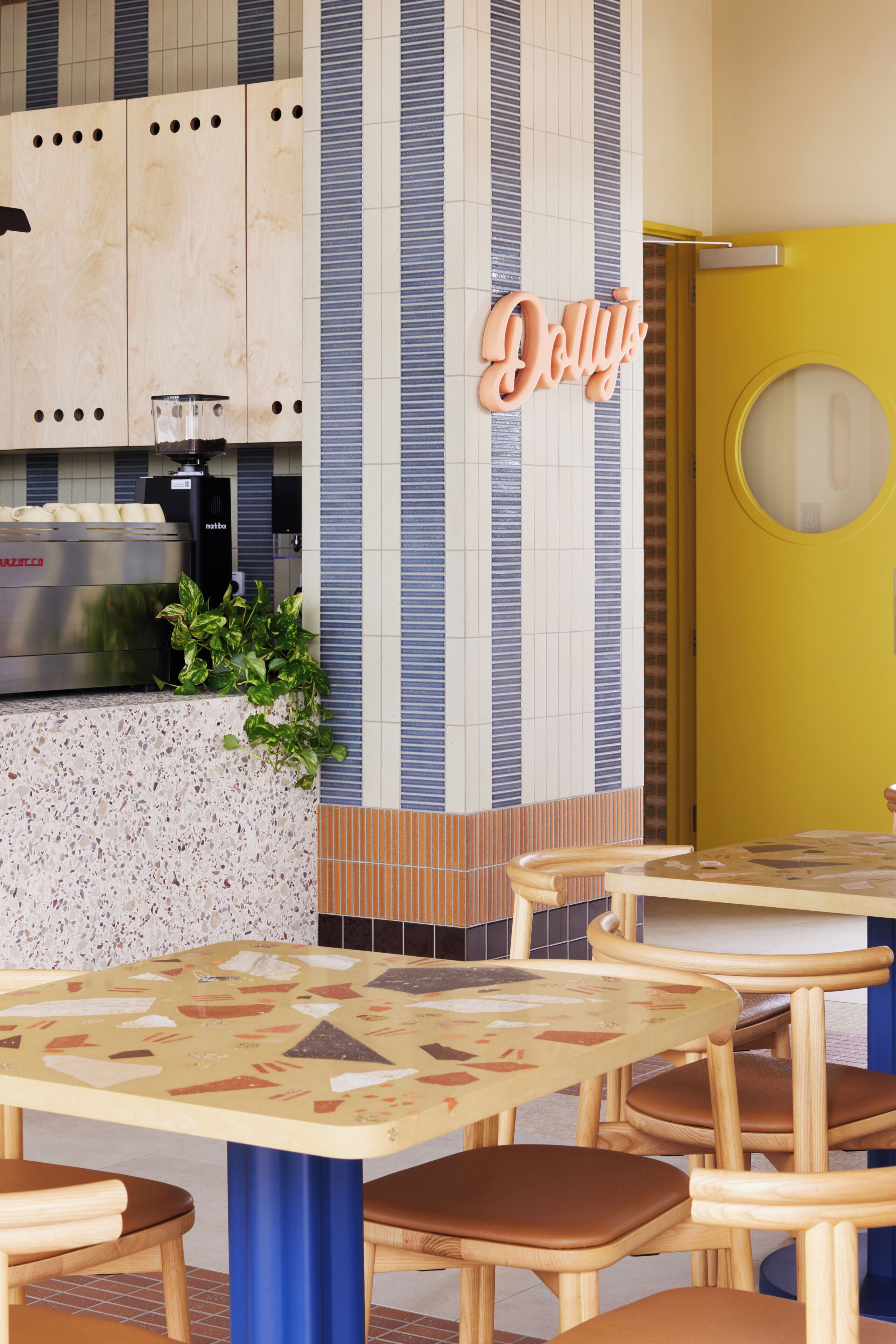 A restaurant interior with a kitchen area, seating arrangement, and a distinctive yellow door.