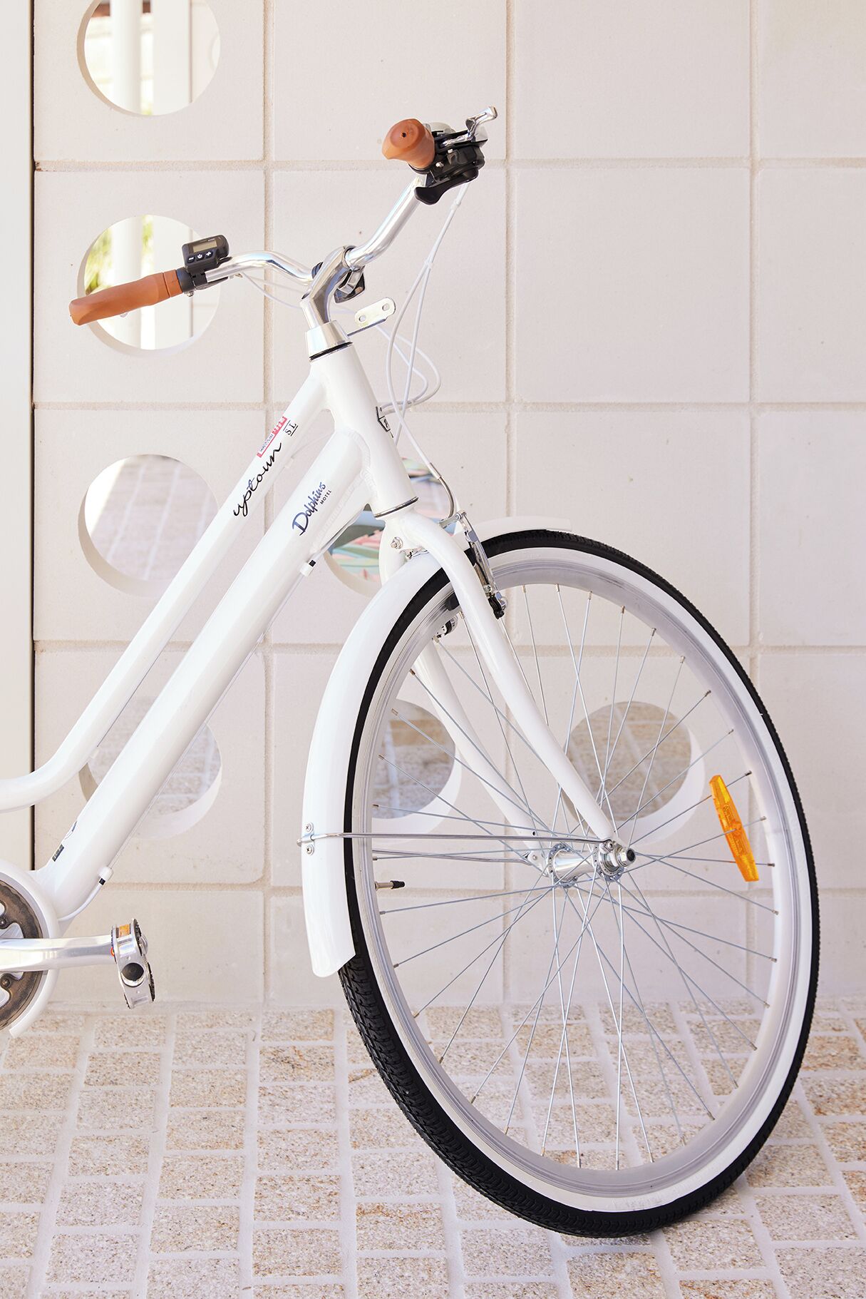 A white bicycle with a digital display, a front suspension fork, and a rear derailleur.