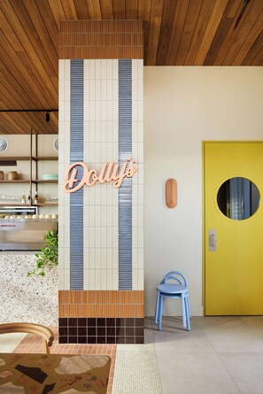 A modern interior with a vertical striped wall, a yellow door, and a blue chair. - Dolphins Motel (Mollymook)