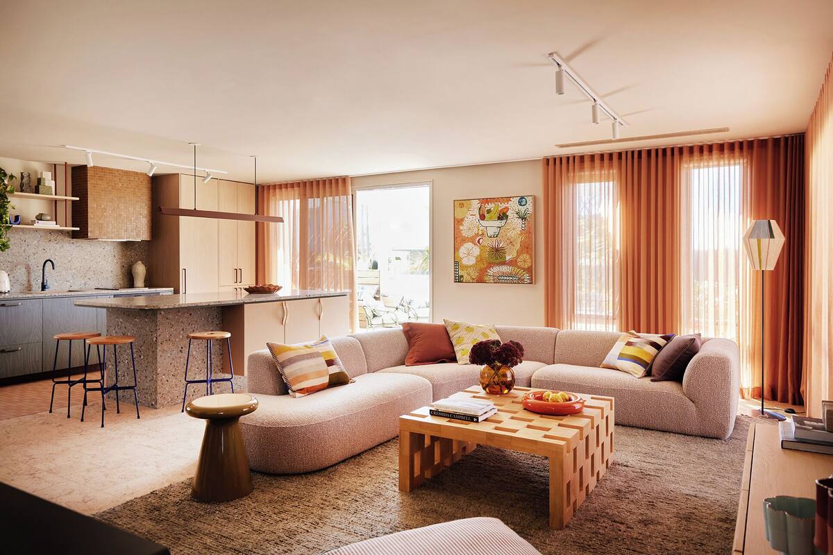 A modern living room with a sofa, coffee table, and kitchen area with bar stools.