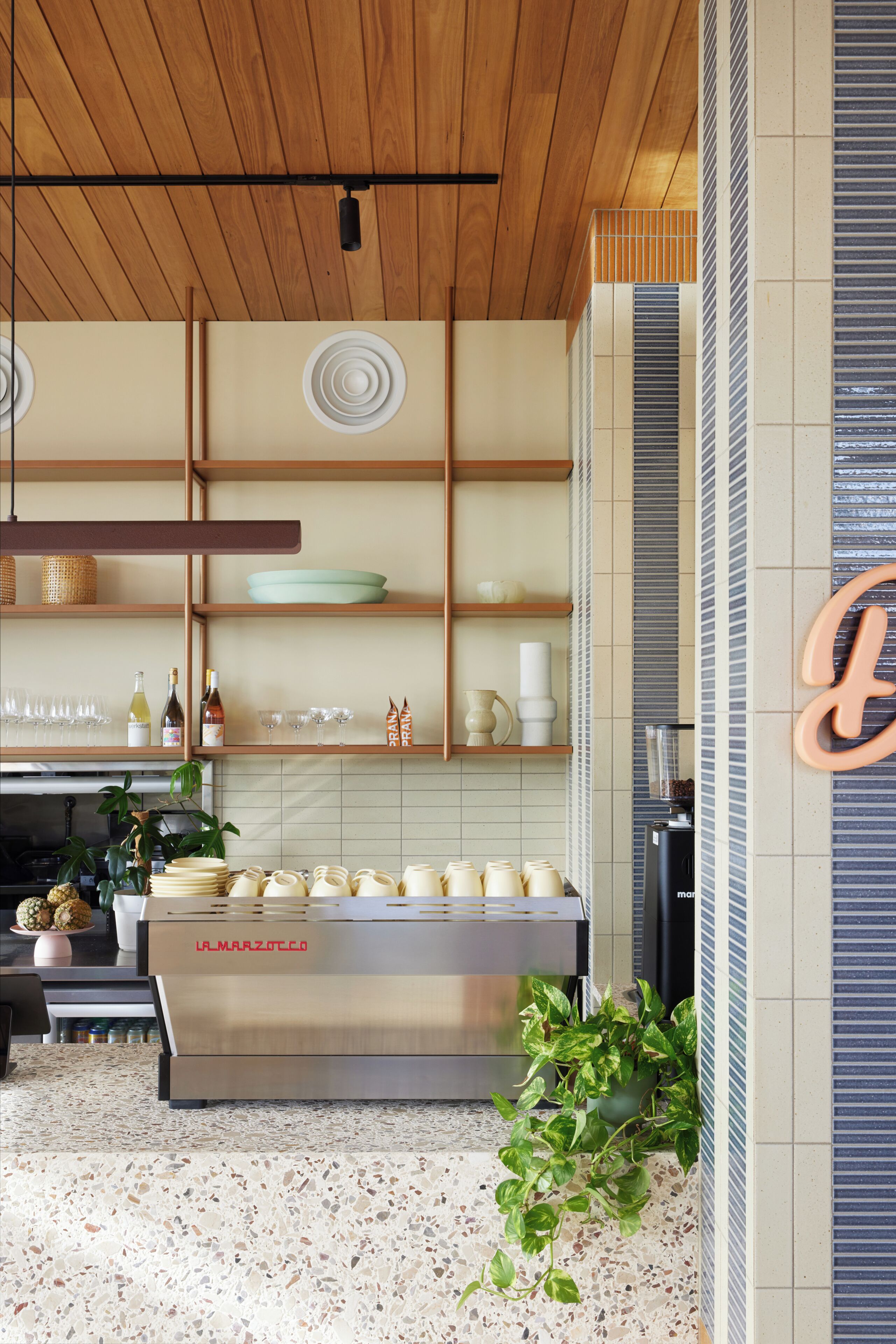 A kitchen with wooden shelves, a stainless steel appliance, and a potted plant.