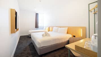 A hotel room with two beds, a desk, and a mirror.
