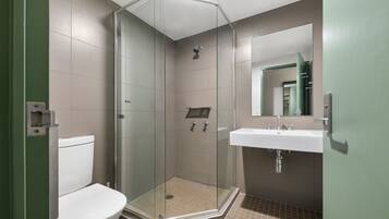 Une salle de bain moderne avec une douche à parois de verre, des toilettes blanches et un lavabo avec un miroir au-dessus.