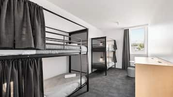 Habitación tipo dormitorio con literas, un escritorio y una ventana con cortinas.