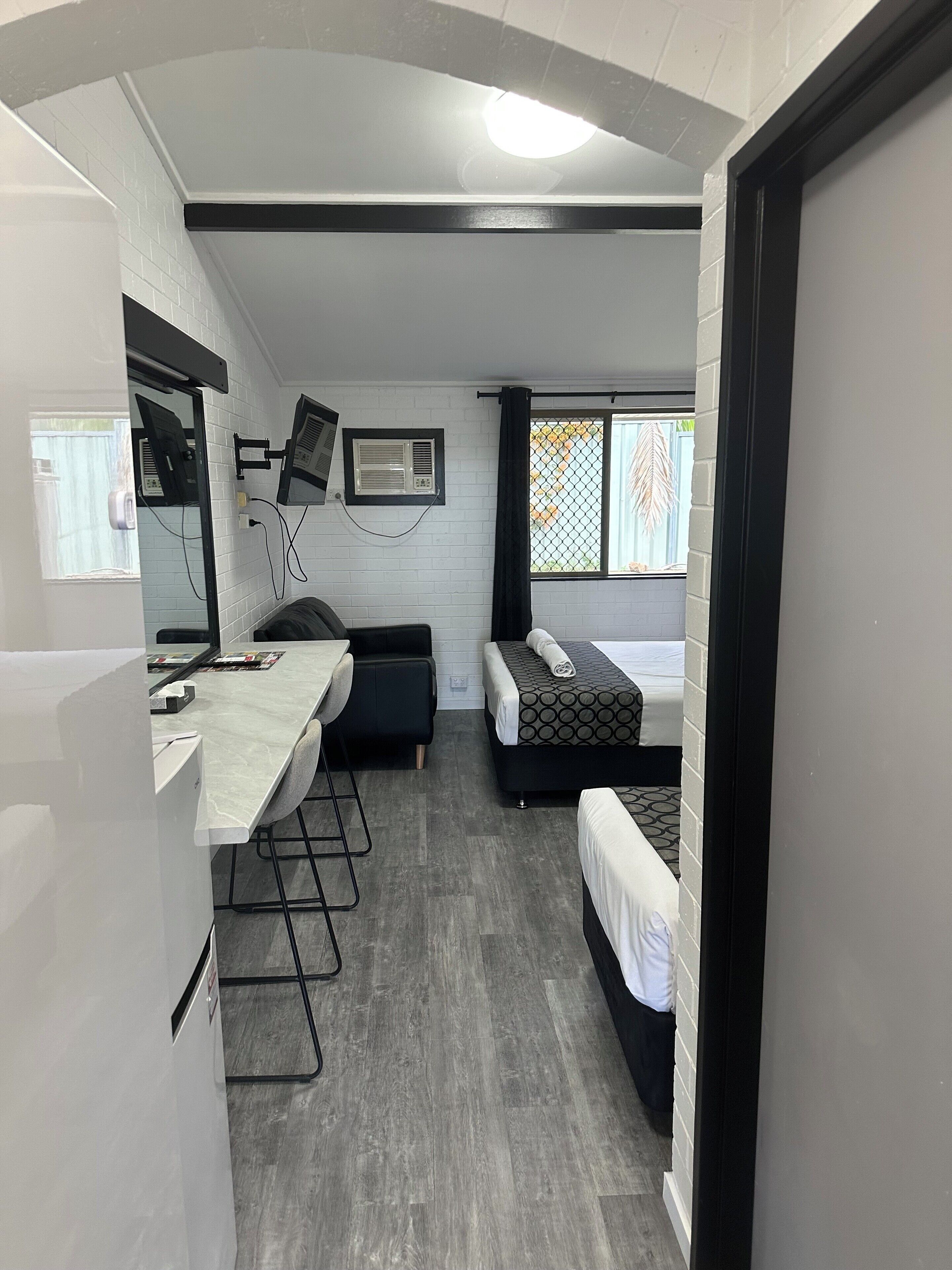 A compact room with a kitchenette, a bed, a desk, and a window with a view.