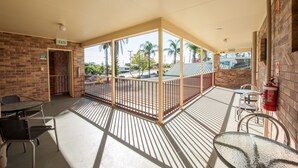 A covered outdoor area with tables and chairs, a brick wall, and an exit sign. - Allan Cunningham Motel (Kearneys Spring)